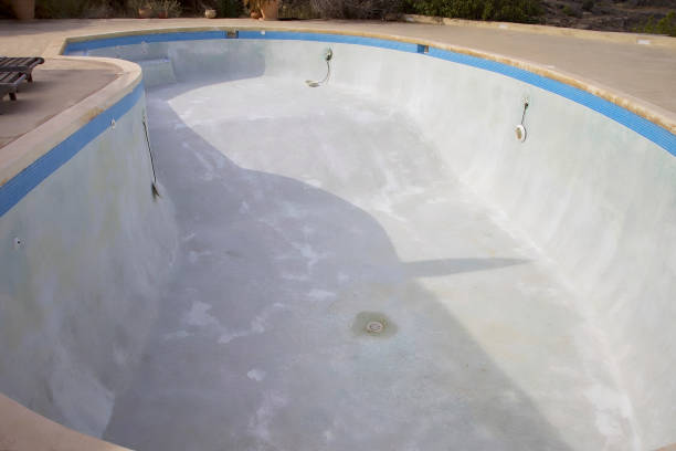 Pool resurfacing crew repairing cracks and worn pool surfaces<br />
