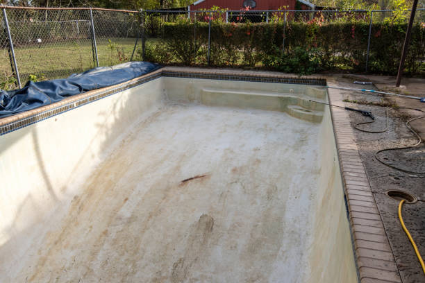 Pool specialist inspecting rough plaster and surface wear with professional preparation tools