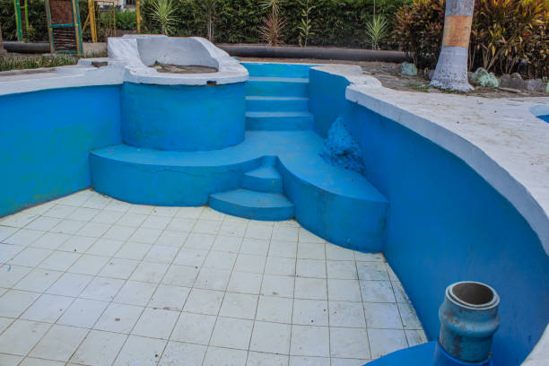 Crew refinishing rough residential pool surface before summer guests arrive at coastal home